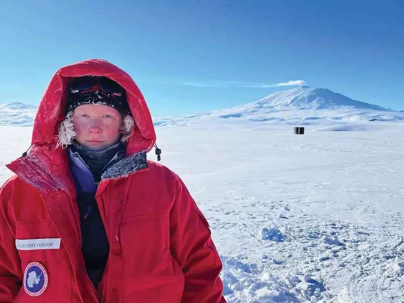 Marissa Tremblay in Antarctica. She is wearing a large red coat with the hood up.