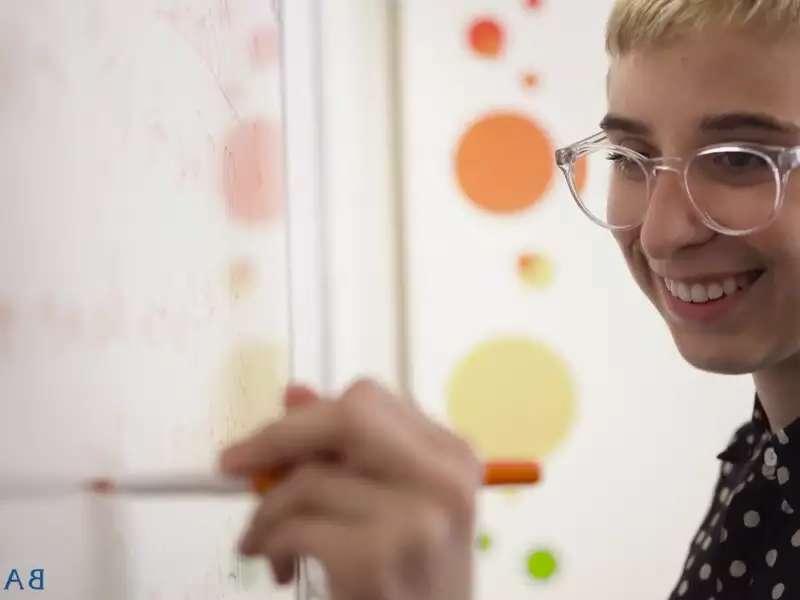 Close up of a white woman writing on a white board